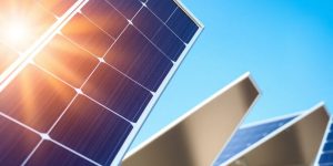 Solar panels under bright sunlight with blue sky.